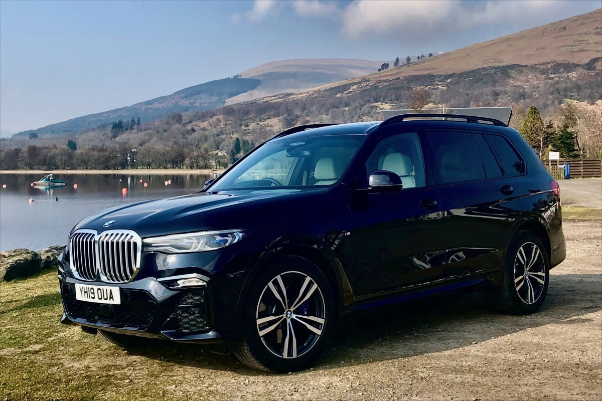 Luxury SUV by scenic lake; ideal for chauffeur services.