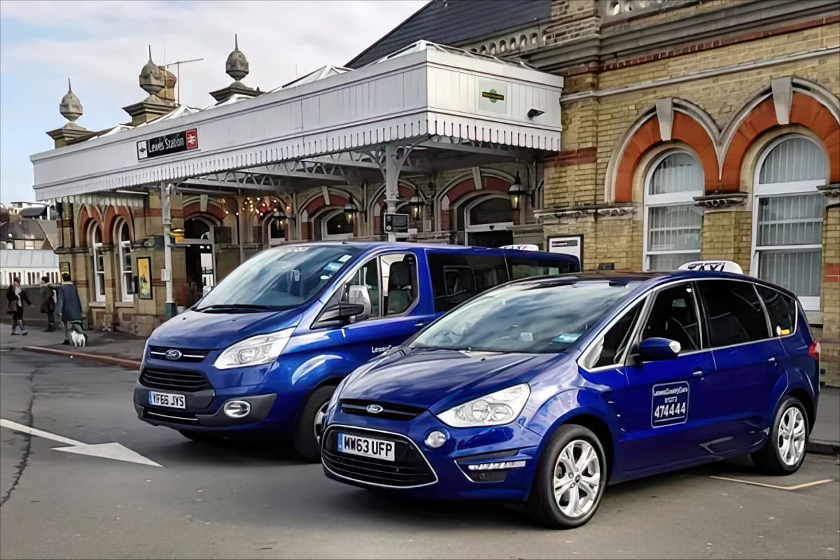 Blue taxis outside Lewes Station, ideal for professional chauffeurs.