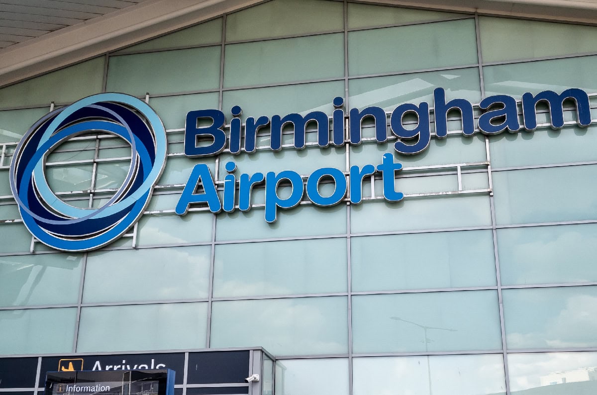Birmingham Airport signage on the building facade, highlighting the airport's modern glass architecture and prominent logo, emphasizing the need for improved driver facilities as called for by GMB.